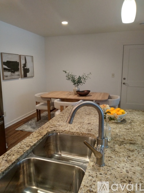 A kitchen with a granite countertop and a stainless steel sink.