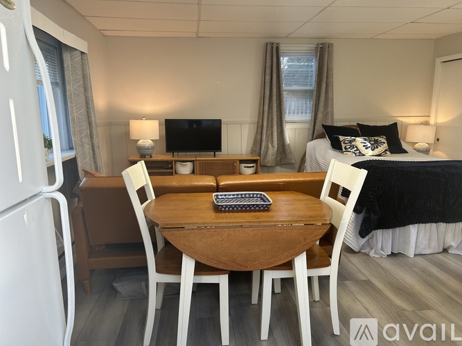 A small room with a bed, a table with chairs, and a refrigerator.