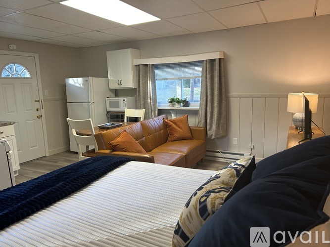 A bedroom with a bed, couch, and kitchenette.