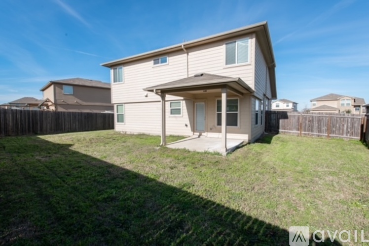 A beige house with a brown fence and a green lawn.