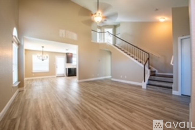 A spacious room with wooden floors and a staircase.