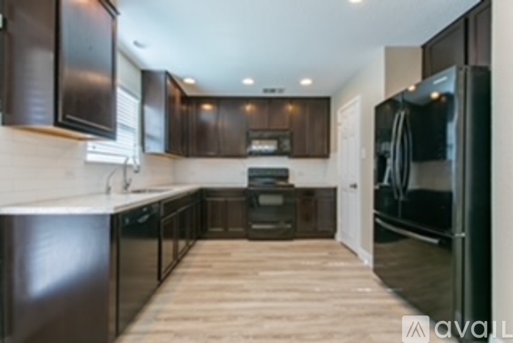 A kitchen with dark brown cabinets and a black refrigerator.