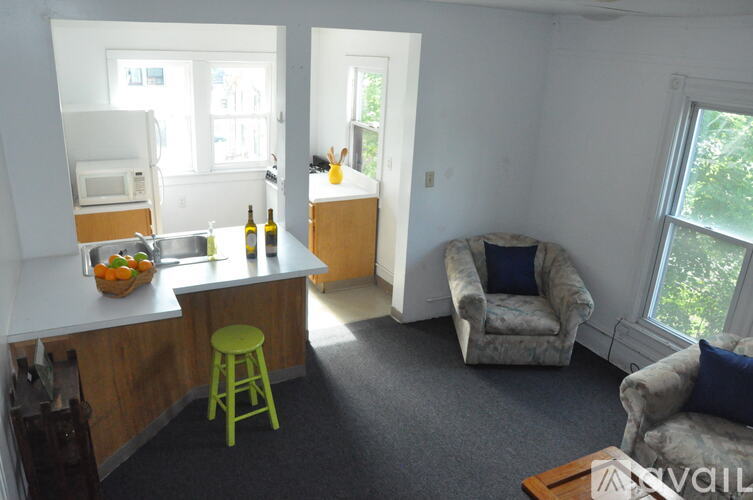 A kitchen with a green stool and a white fridge.