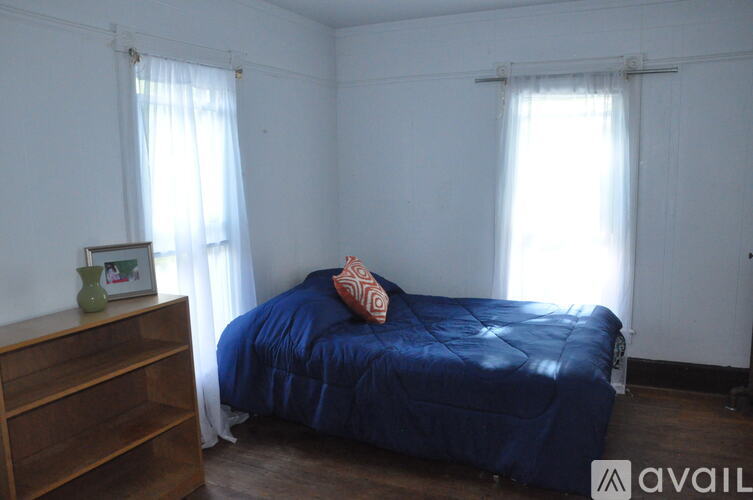 A bedroom with a blue bedspread and a wooden dresser.