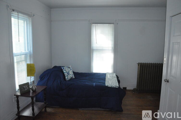 A bedroom with a bed, nightstand, and window.
