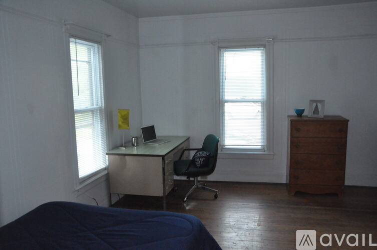 A room with a bed, desk, and chair.