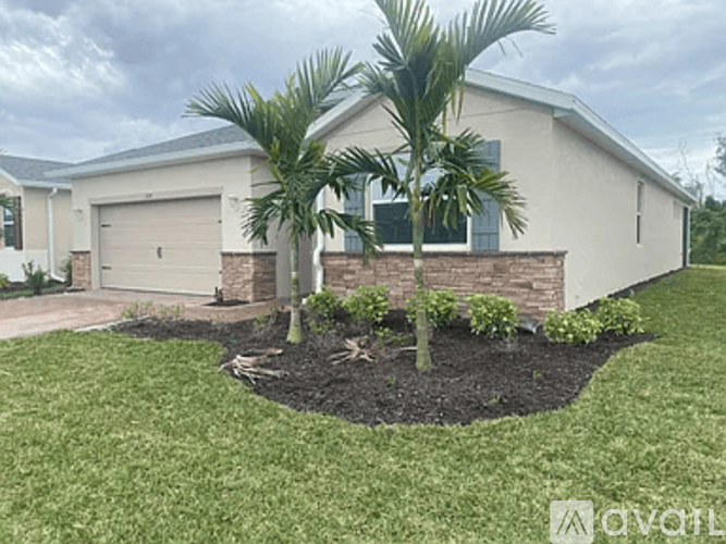 A house with a driveway and a palm tree in front.