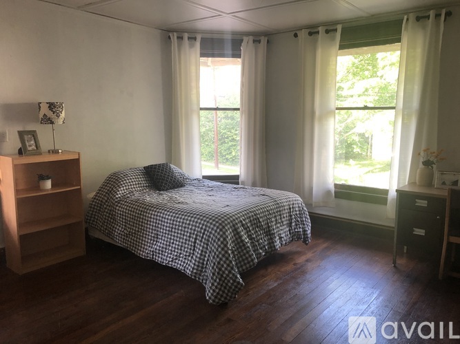 A bedroom with a bed, nightstand, and window.
