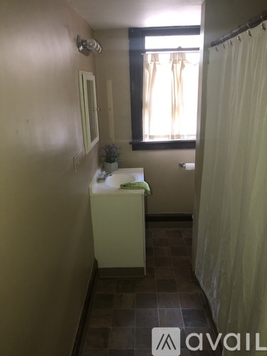 A bathroom with a white sink and a window with curtains.
