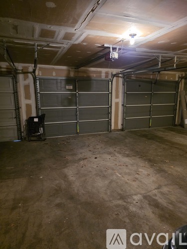 A spacious garage with a concrete floor and a ceiling with exposed beams and a light fixture.
