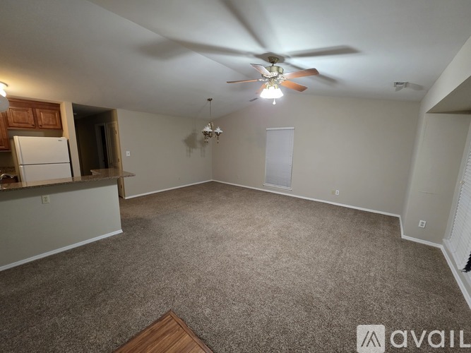 A spacious living room with a ceiling fan and a chandelier.