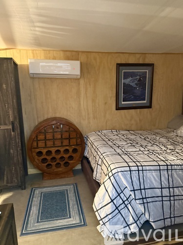A bedroom with a bed, chair, and picture on the wall.