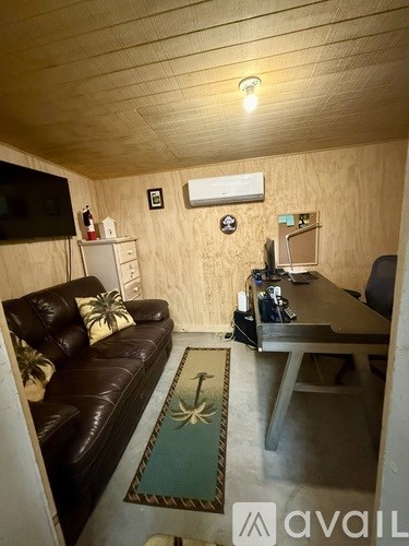 A living room with a brown leather couch and a television mounted on the wall.