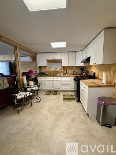 A kitchen with white cabinets and a wooden island.