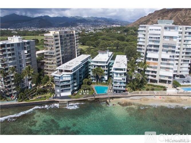 A beachfront resort with a swimming pool and a mountain in the background.