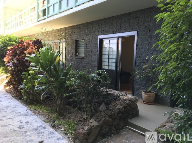A house with a brown door and a stone wall in front of it.