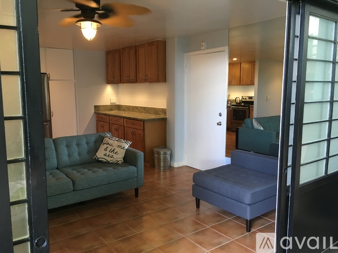 A living room with a green couch and a fan on the ceiling.