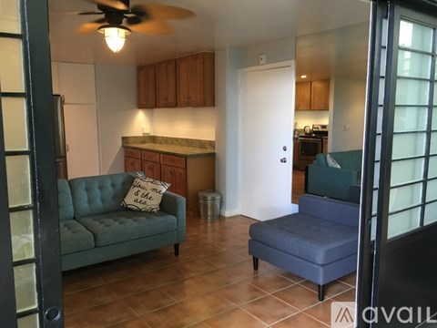 A living room with a green couch and a fan on the ceiling.