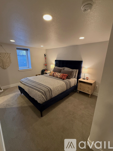 A bedroom with a bed, nightstand, and window.