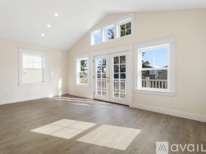 A spacious room with hardwood floors and a large window.