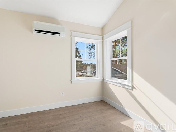 A room with a window showing a view of trees and a building outside.