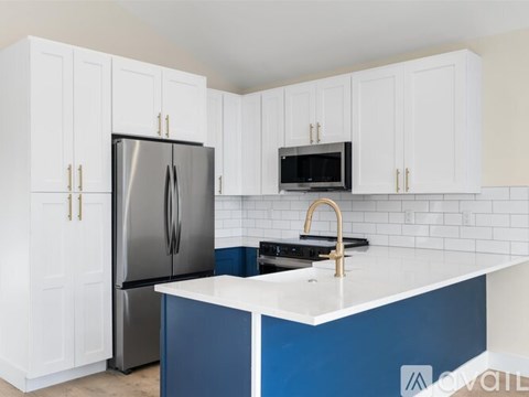 A kitchen with white cabinets and a blue island.