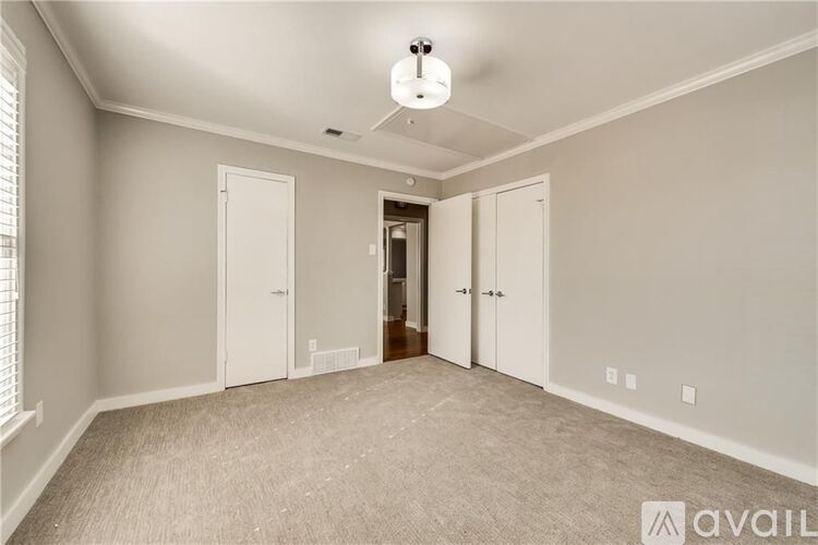 A spacious room with a carpeted floor and a ceiling fan.