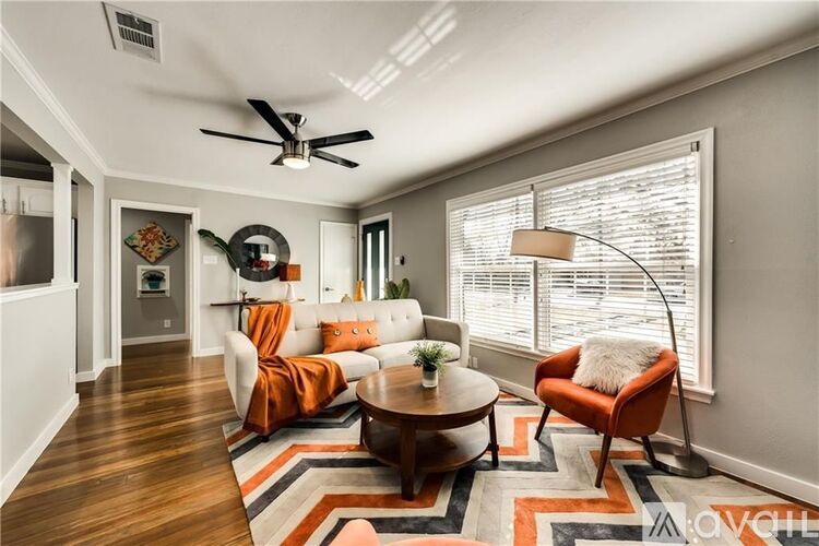 A living room with a brown coffee table and two orange chairs.