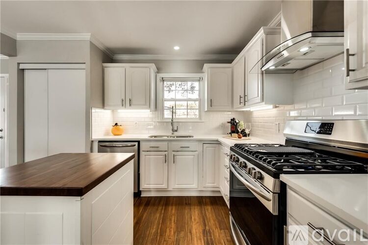 A modern kitchen with white cabinets and a wooden countertop.