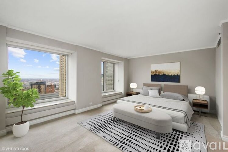 A bedroom with a large bed, a potted plant, and a view of the city through the window.