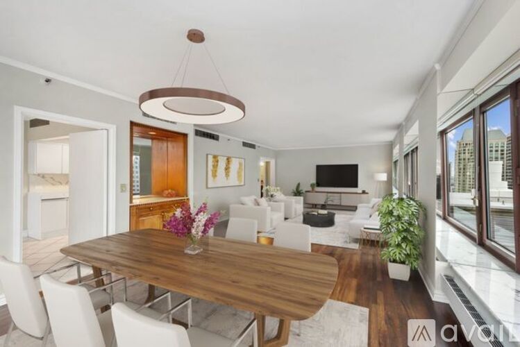 A modern dining room with a wooden table and white chairs.
