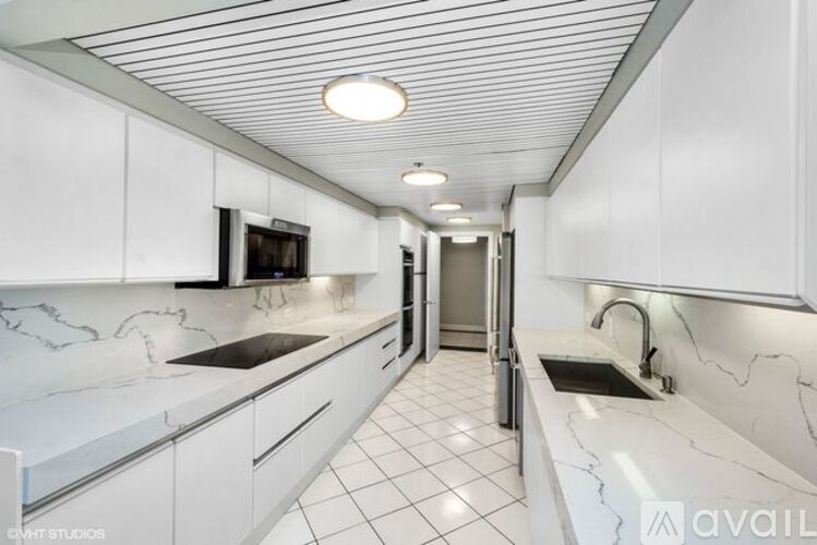 A modern kitchen with white cabinets and marble countertops.
