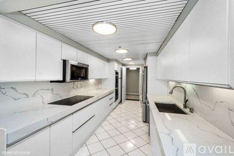 A modern kitchen with white cabinets and marble countertops.