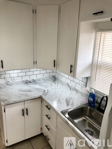 A kitchen with white cabinets and a marble countertop.