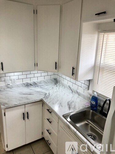 A kitchen with white cabinets and a marble countertop.