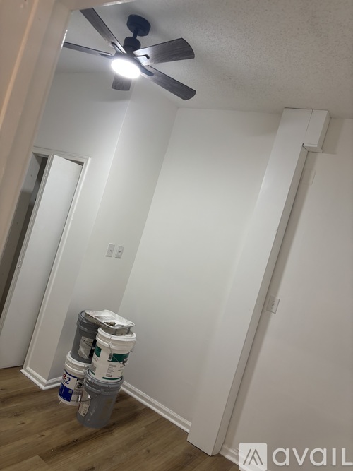 A room with a ceiling fan and two buckets of paint.