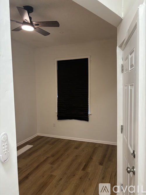 A room with a ceiling fan and wooden flooring.