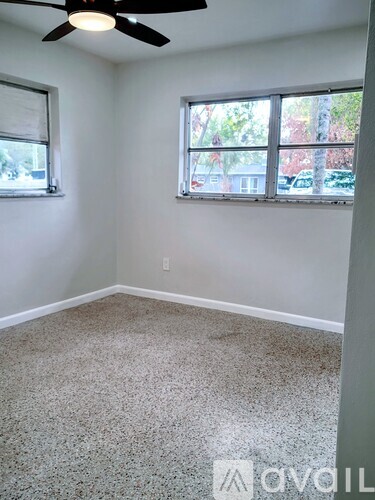 A room with a ceiling fan and two windows.