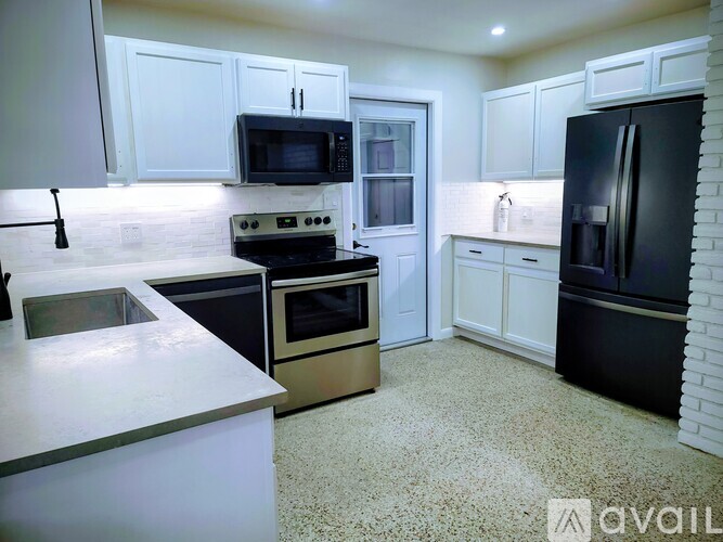 A kitchen with white cabinets and black appliances.
