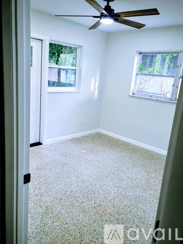 A room with a ceiling fan and two windows.
