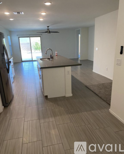 A kitchen with a refrigerator, sink, and a ceiling fan.