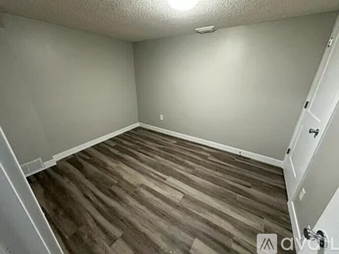 A room with wooden flooring and white walls.