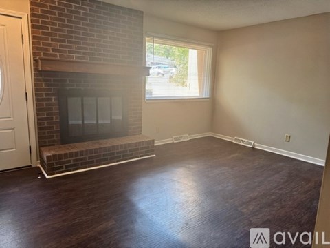 A room with a brick fireplace and wooden flooring.