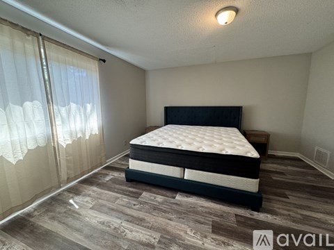 A bedroom with a large bed and wooden flooring.