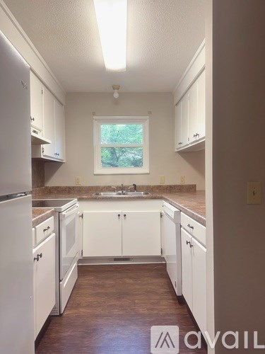 A kitchen with white cabinets and a window.
