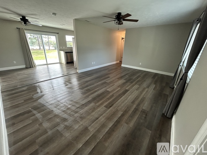 A spacious room with wooden flooring and a ceiling fan.