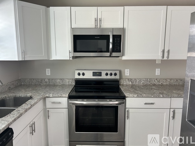 A kitchen with white cabinets and a stove top oven.