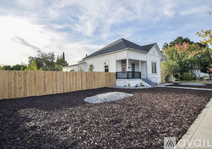 A white house with a black roof and a wooden fence.