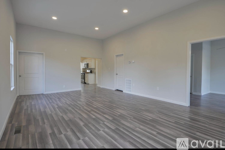 A spacious room with wood flooring and white walls.