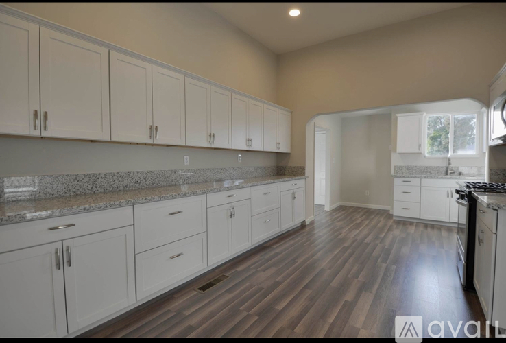 A kitchen with white cabinets and a wooden floor.